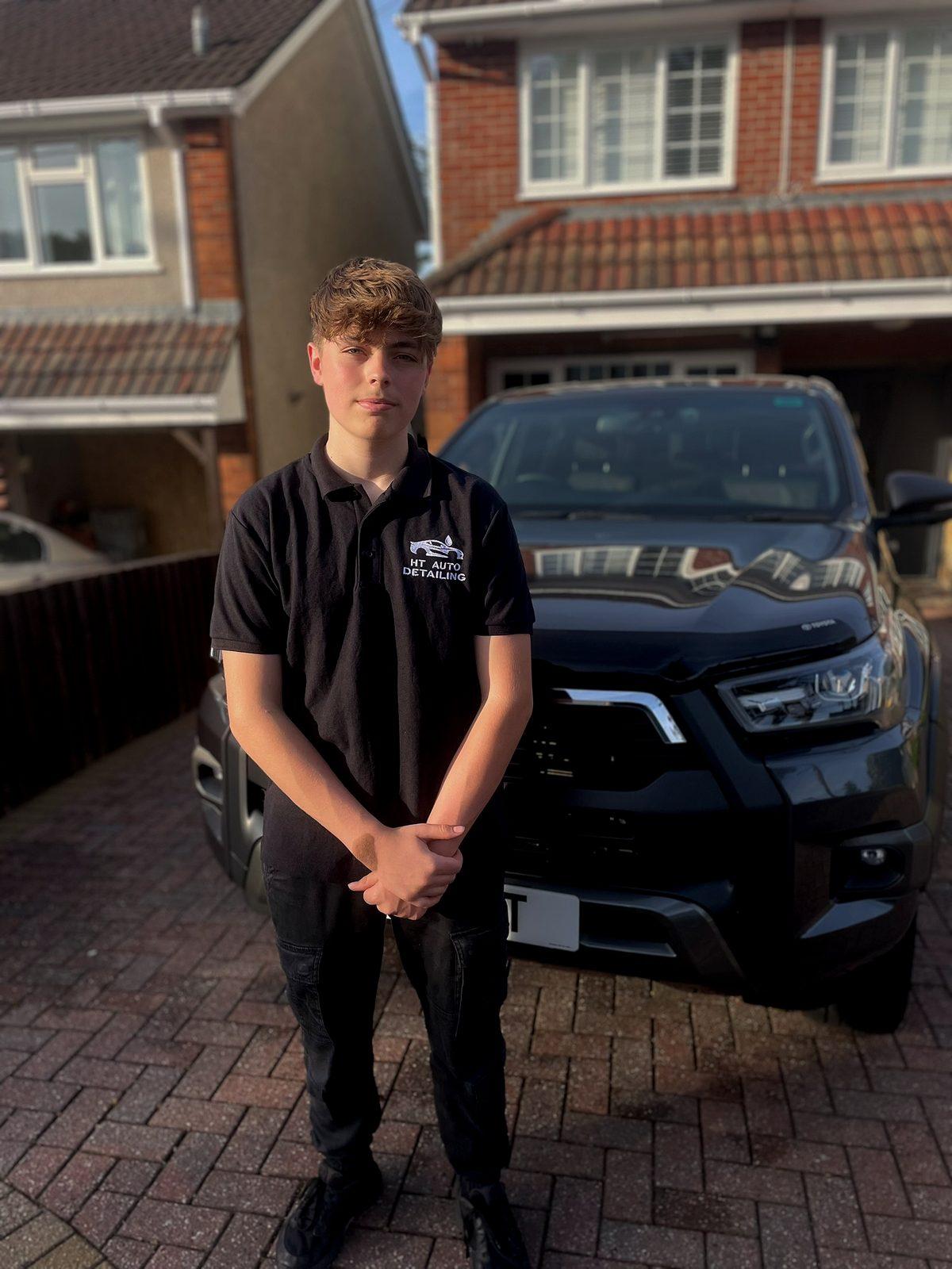 The owner of HT Auto Detailing in his branded polo beside a black Toyota Hilux